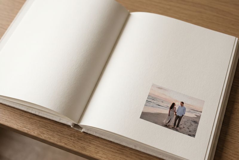 Open photo book with a single small photograph on an otherwise empty cream page